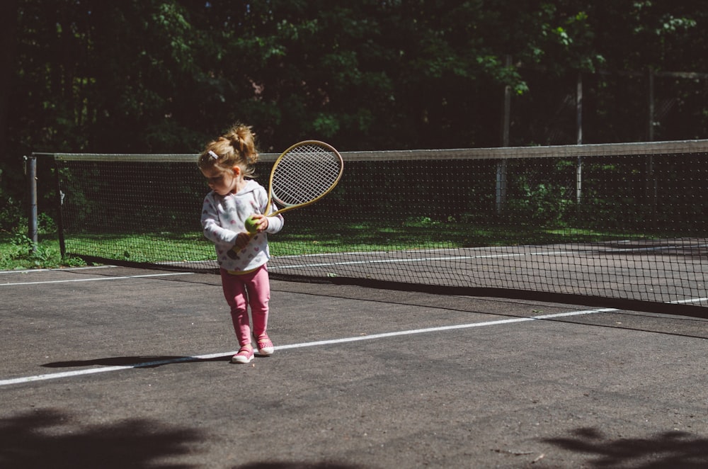 Ragazza che tiene la racchetta da tennis mentre si trova accanto alla rete bianca e nera