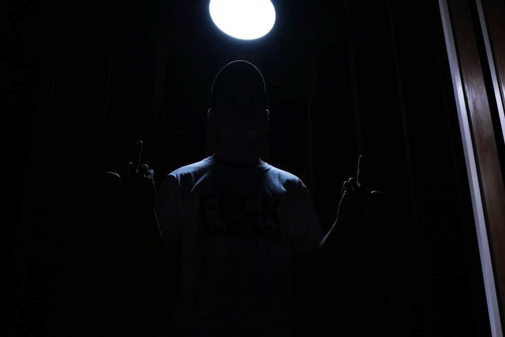 a man standing in the dark with his hands up