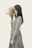 woman wearing gray and black striped long-sleeved dress holding white petaled flowers
