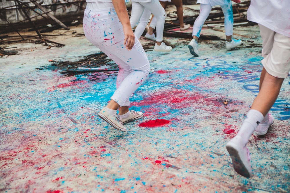 persone che calpestano il pavimento con vernici spruzzate di blu e rosso