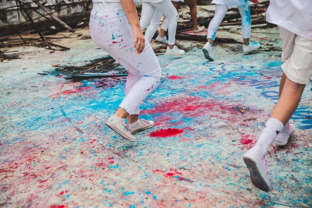 people stepping on floor with blue and red splattered paints