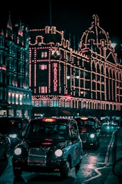 black taxi in the street passing trough Harrods Mall during nighttime