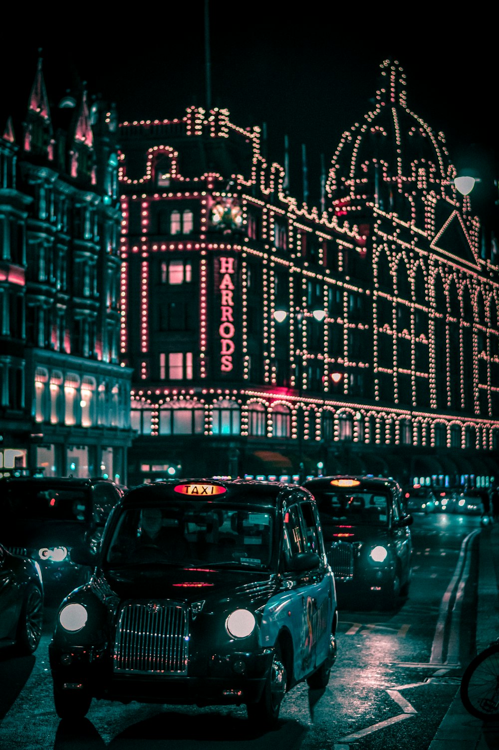 taxi negro en la calle que pasa por el centro comercial Harrods durante la noche