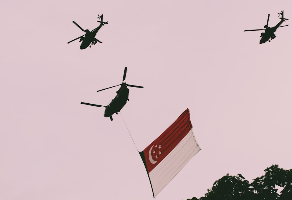 Photo de trois hélicoptères et d’un avec drapeau