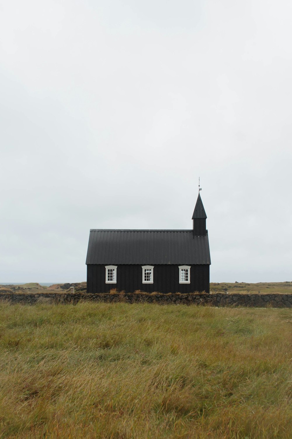 black and white barn on green grass field near concrete fence