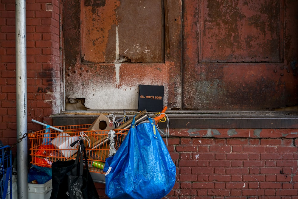 Sac bleu accroché à un chariot d’épicerie orange près d’un mur de briques