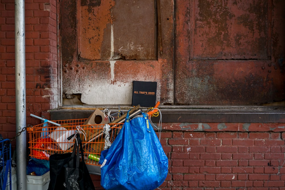 blue bag hanging on orange grocery cart near bricked wall
