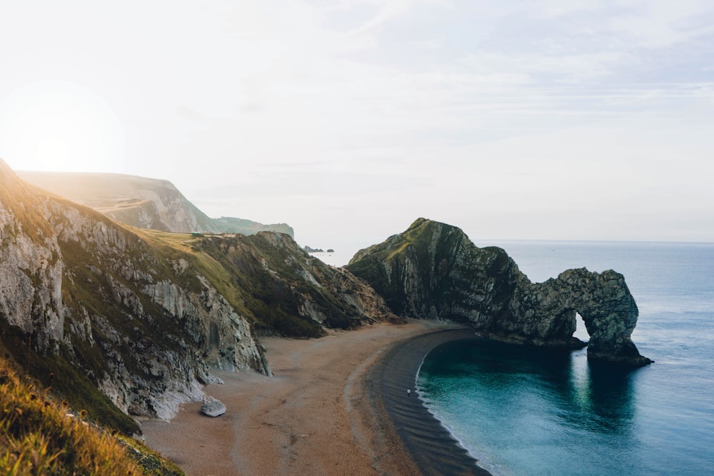 aerial view photography of rock formations beside ocean under cloudy sky during daytime