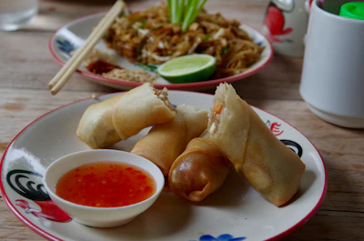 Vibrant plate of crispy spring rolls served with a tangy dipping sauce on a rustic wooden table.