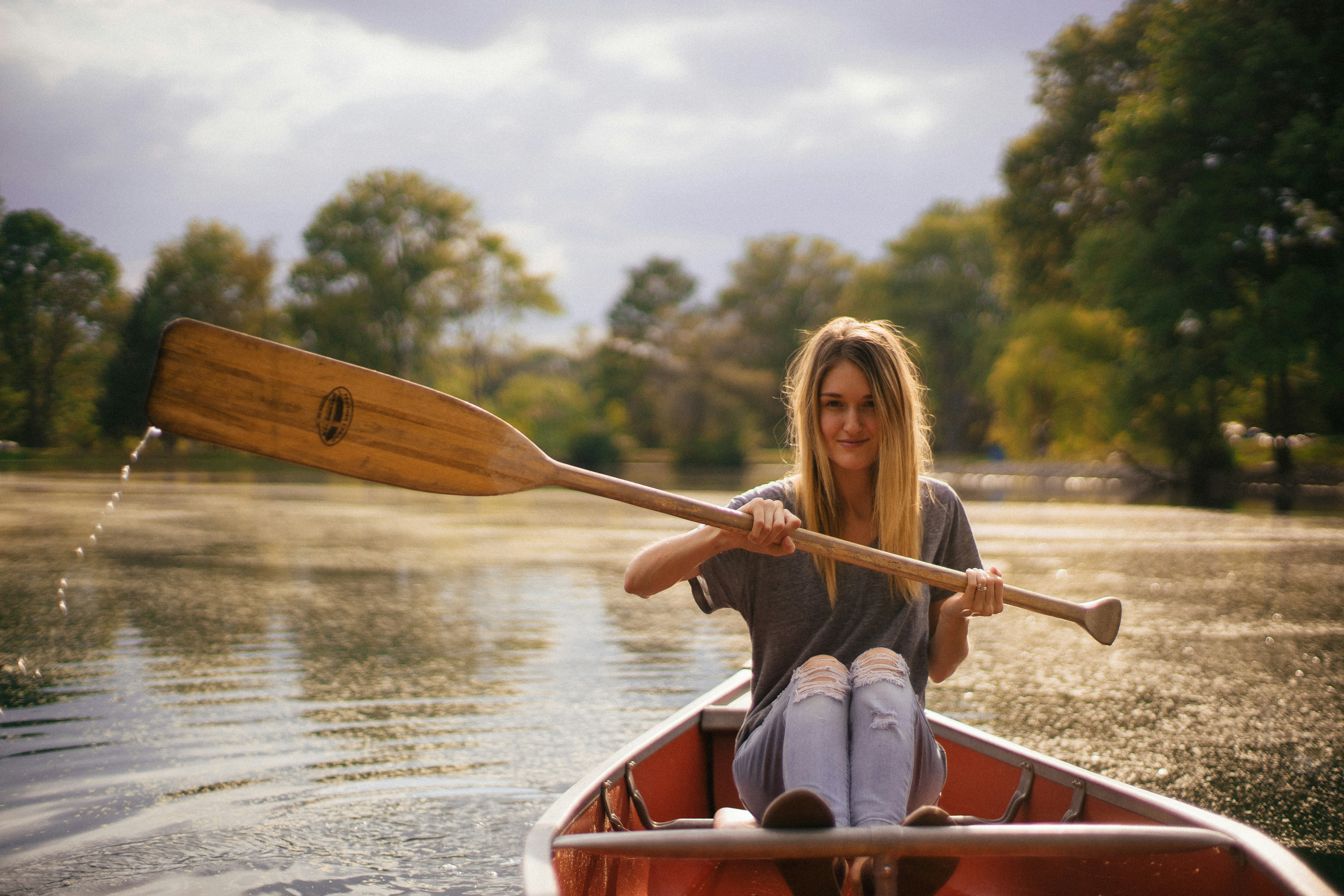 woman sitting in brown paddle boat.