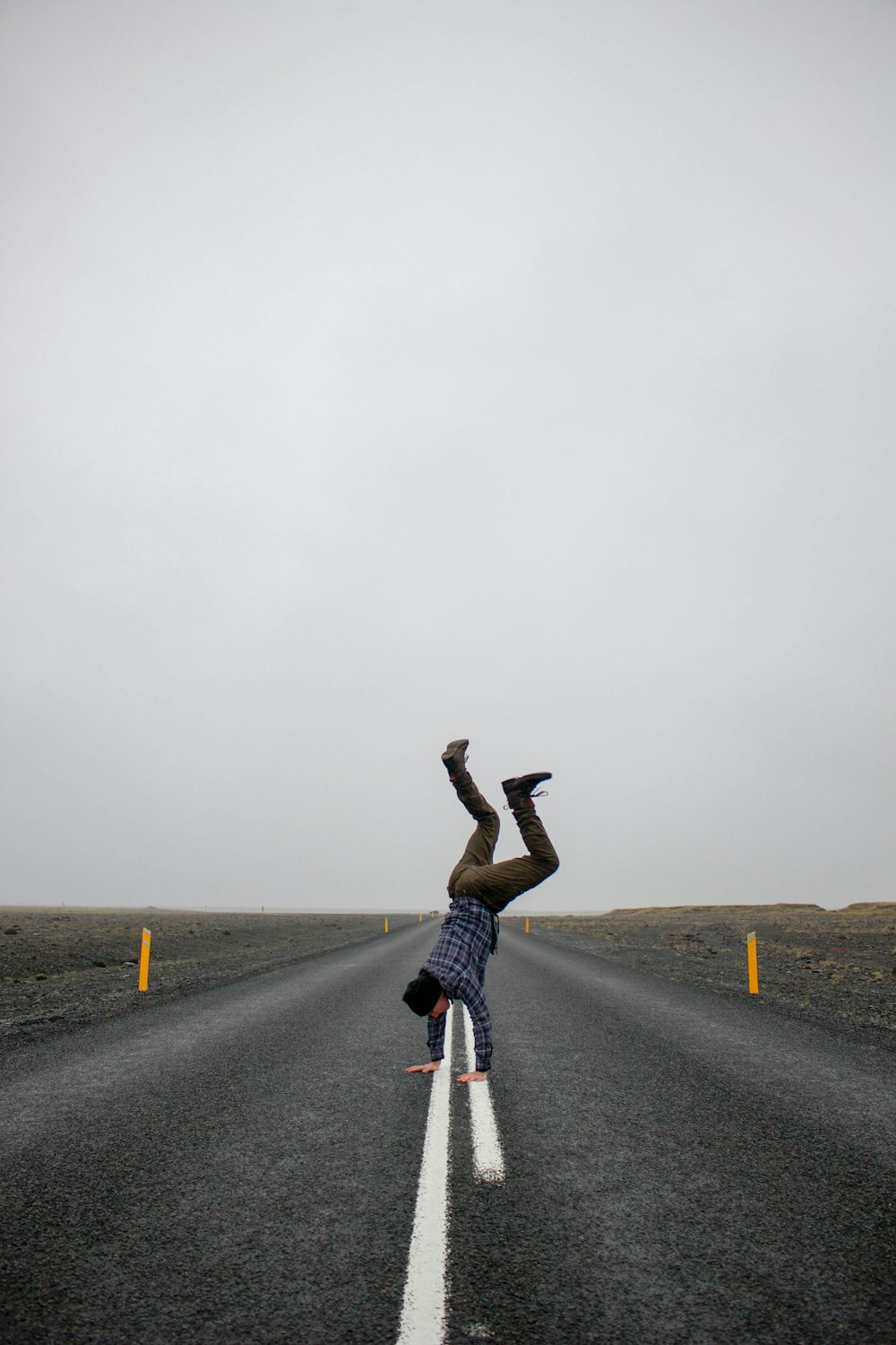 man doing handstand on middle of concrete pavement