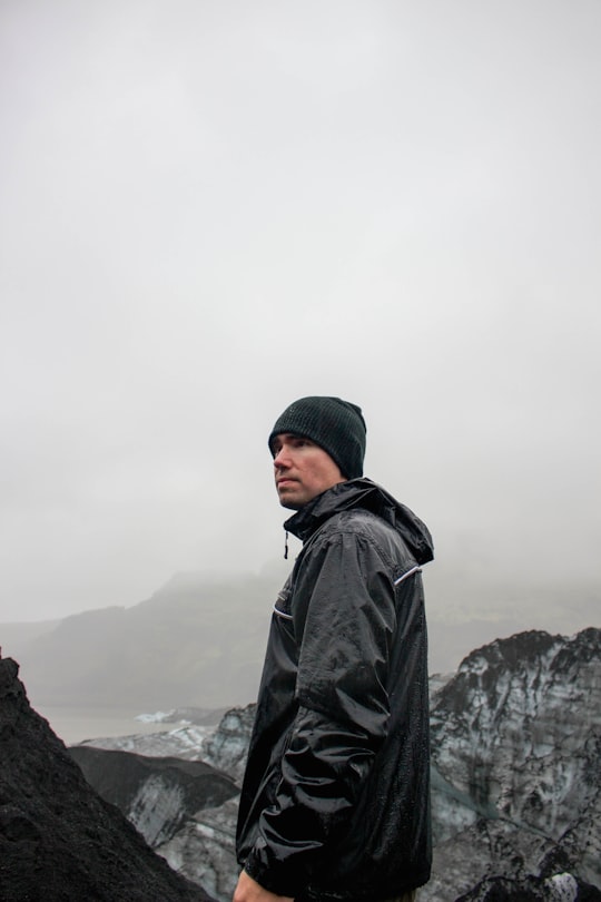 man stands on top of the mountain in Sólheimajökull Iceland