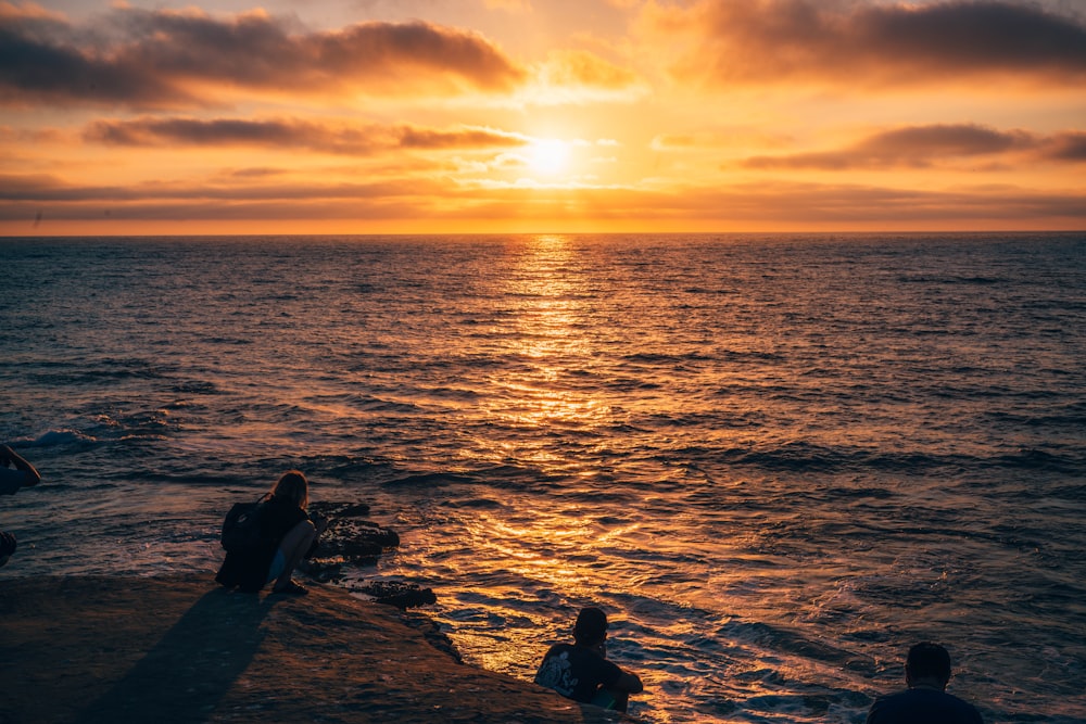 Silueta de los hombres en el cuerpo de agua durante la puesta del sol