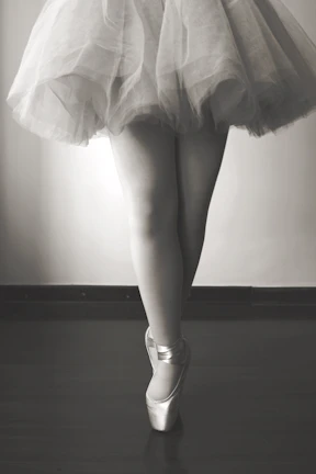 A minimalist shot of a ballet dancer’s poised foot against a deep black background.