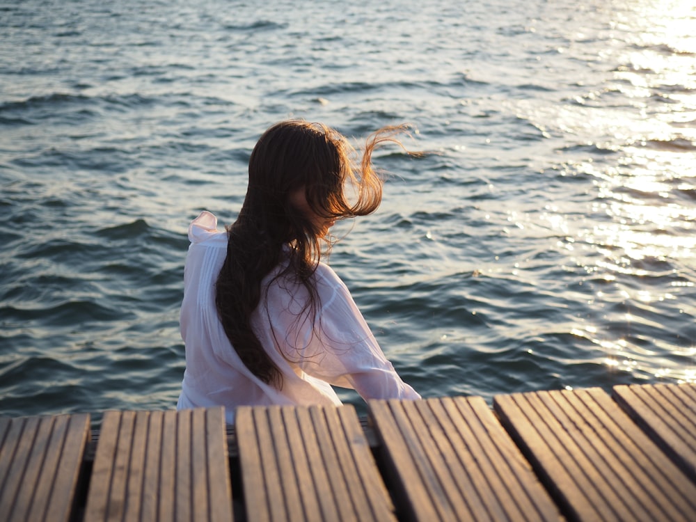 woman wearing white long-sleeved top near body of water
