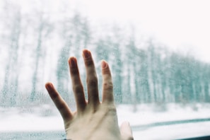 A close-up of a child's hand gently touching a window fogged with breath, symbolizing quiet reflection.