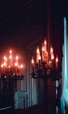 An ornate gilded mirror reflecting the soft glow of candlelight in a classic French mansion room.