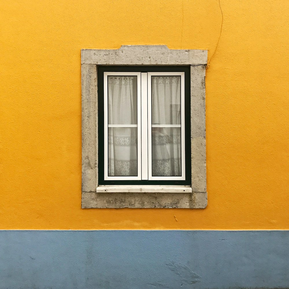 Foto del cristal blanco de la ventana contra la pared amarilla