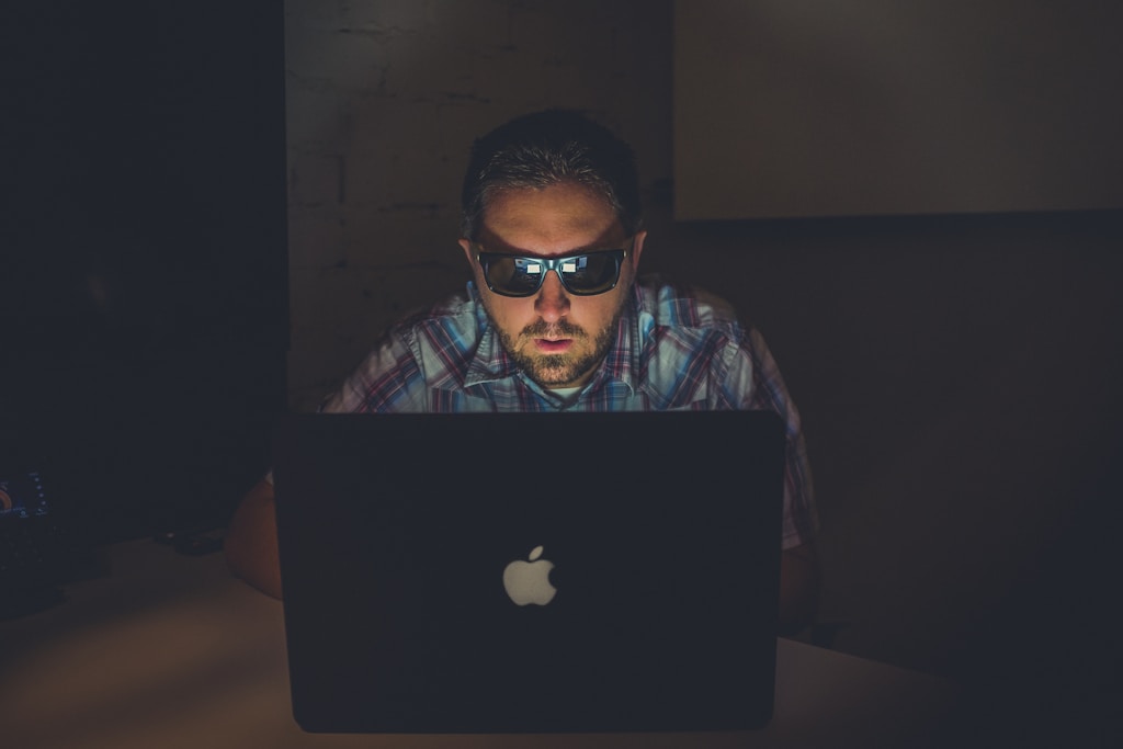 man wearing sunglasses using MacBook