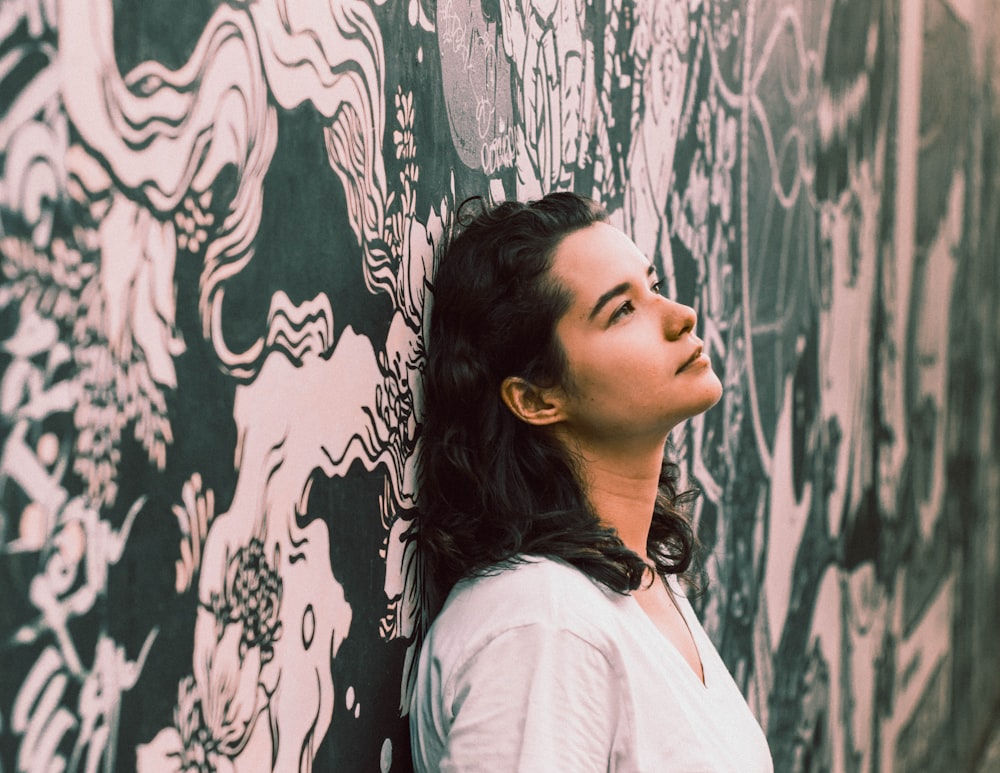 woman in white V-neck shirt leaning on wall