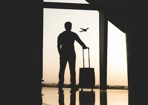Homme d'affaires avec sa valise devant une baie vitrée, en déplacement professionnel à Rabat