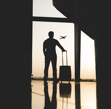 silhouette of man holding luggage inside airport