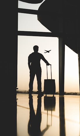 silhouette of man holding luggage inside airport