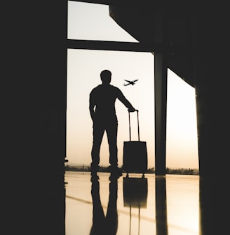 silhouette of man holding luggage inside airport