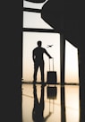 silhouette of man holding luggage inside airport