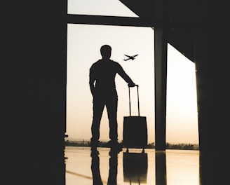 silhouette of man holding luggage inside airport