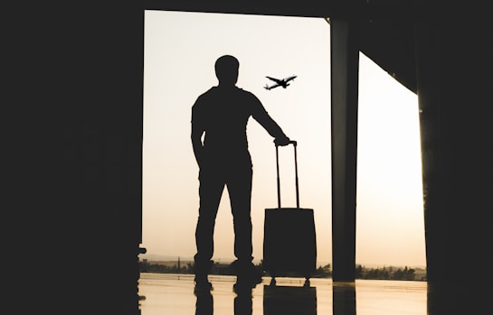 silhouette of man holding luggage inside airport