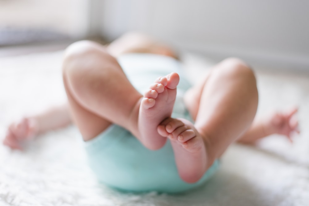 Baby wiggles their toes and lies on their back in a blue onesie