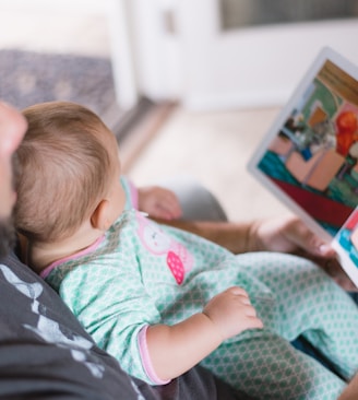 person carrying baby while reading book