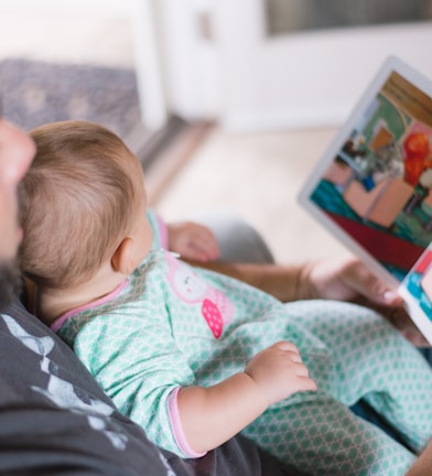 person carrying baby while reading book