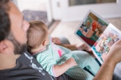 person carrying baby while reading book