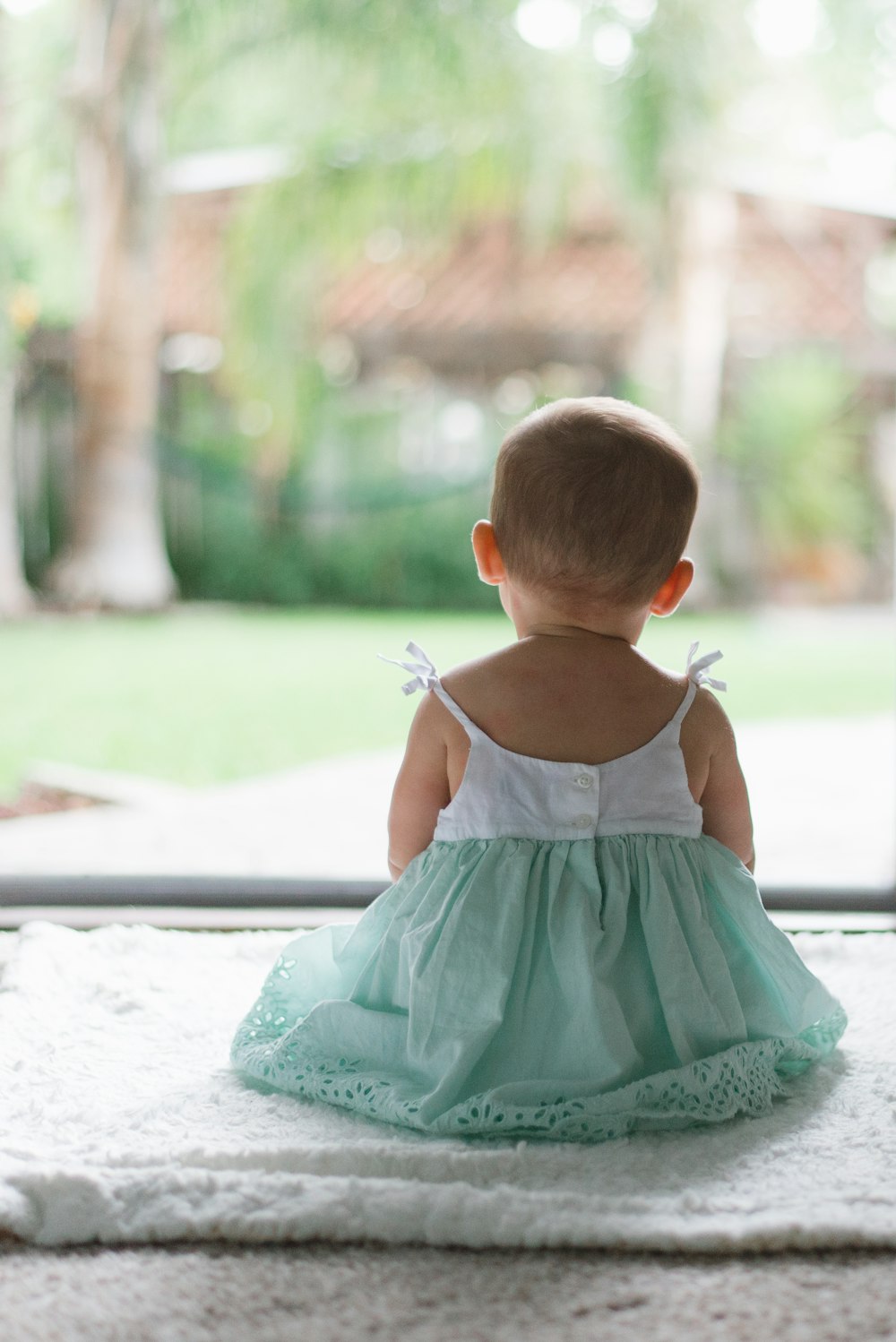 selective focus photo of toddler wearing sleeveless dress sitting on floor