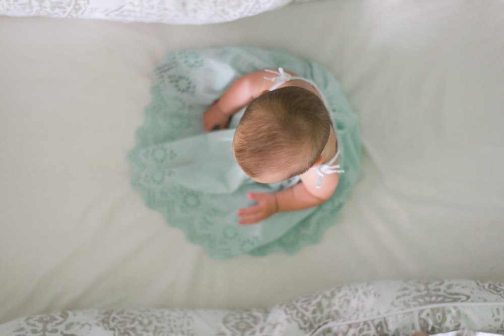 baby sitting on white textile