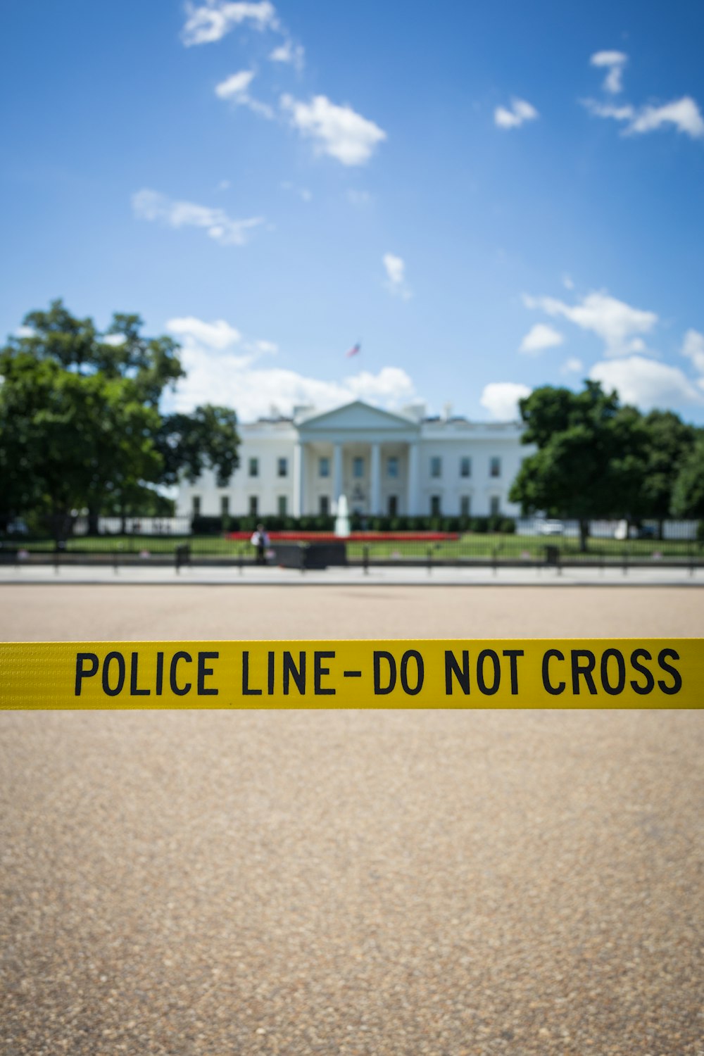 Police line-do not cross stanchion near trees under blue sky at daytime