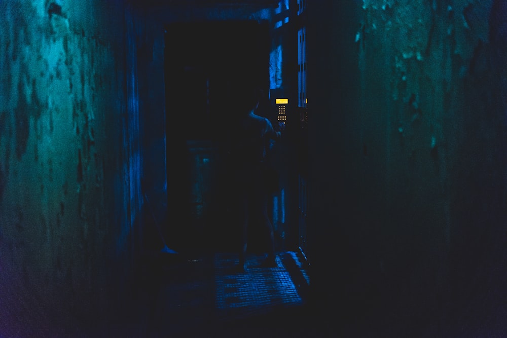 um corredor escuro com uma pessoa em pé na porta