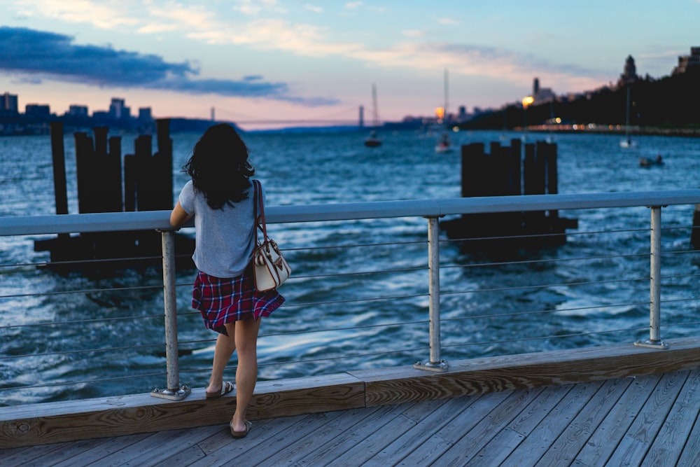 woman standing beside handrail overlooking body of water