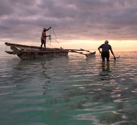 Fishermen working together on a boat at sunrise.