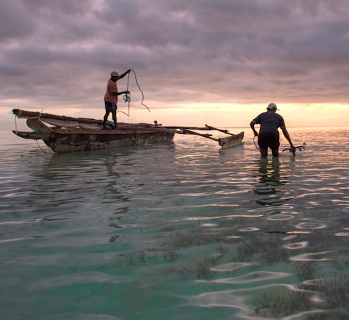 Local fishermen working near a small renewable energy installation by the coast at sunrise.