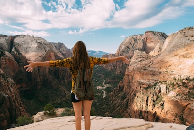 woman spreading her hands white standing on mountain cliff girl teams background