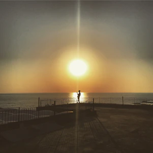 Sunset over the Pacific Ocean viewed from a sleek, modern balcony overlooking Cayucos coastline.