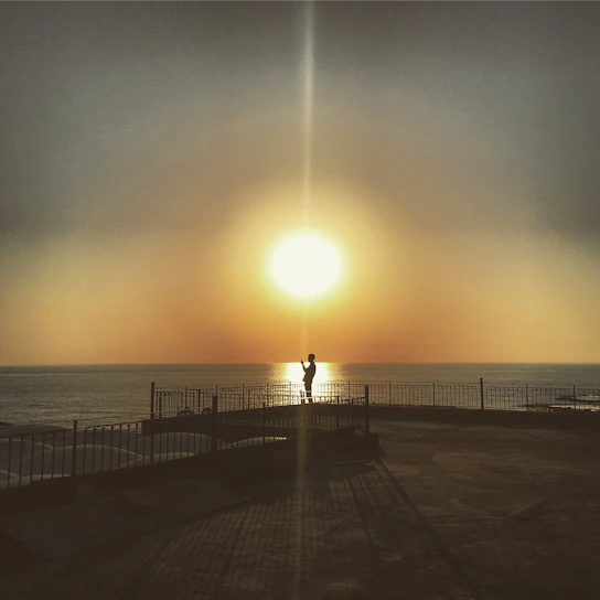 Sunset over the Pacific Ocean viewed from a sleek, modern balcony overlooking Cayucos coastline.