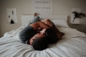 A man and woman cuddling together in bed.