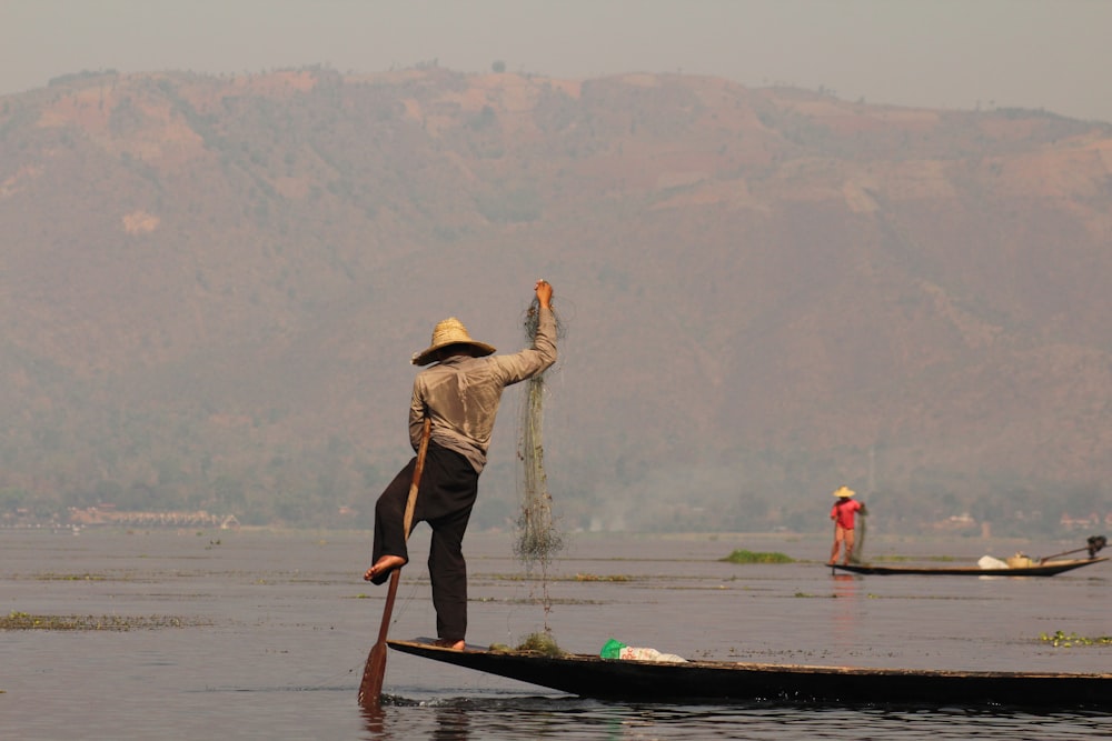 homem em pé no barco e pesca