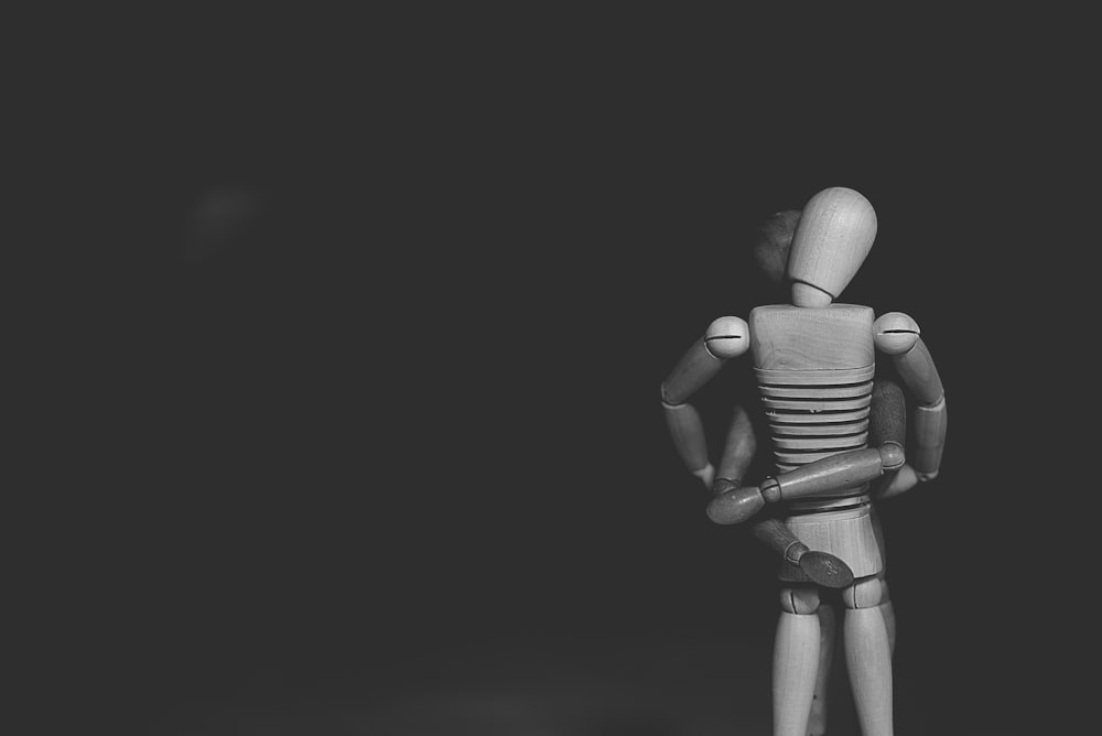 grayscale photo of joint action figure hugging one another