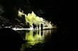 A group of tourists exploring a cave surrounded by tropical vegetation.