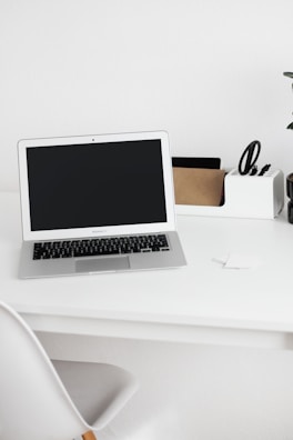 A minimalist workspace featuring a laptop and a simple, sturdy paper tray.